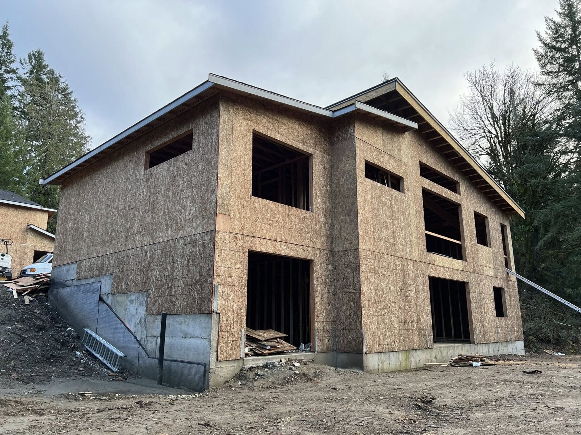 Two-story house framing with OSB sheathing and modern roofline on concrete foundation